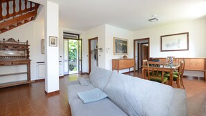 Un salón espacioso con un sofá, una mesa de comedor de madera y una escalera.