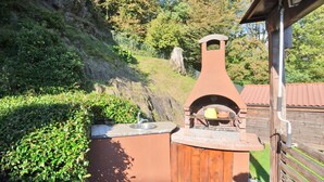 Una cocina al aire libre con chimenea, un lavamanos y una terraza de madera.