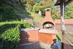 An outdoor kitchen with a chimney, a sink, and a wooden deck.