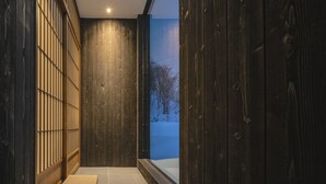 Ein Korridor mit Holzwänden und Blick auf eine verschneite Landschaft.
