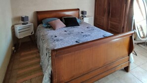 A bedroom with a wooden ceiling, a bed with a floral bedspread, two bedside tables with lamps, and a wooden wardrobe. - Country house, close to footpaths, 5km base de loisirs, 15mn Zoo (Saint-Jean-de-la-Motte)