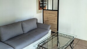 A modern living room with a grey sofa, a glass coffee table, and a wooden ceiling. - Country house, close to footpaths, 5km base de loisirs, 15mn Zoo (Saint-Jean-de-la-Motte)