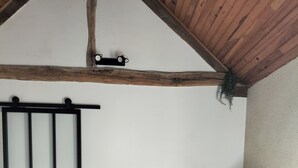 A room with a wooden ceiling, a TV on a black stand, a glass table, and a wooden panel wall. - Country house, close to footpaths, 5km base de loisirs, 15mn Zoo (Saint-Jean-de-la-Motte)