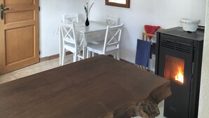 A room with a wooden dining table, white chairs, a clock, a window with blinds, a fireplace, and a door. - Country house, close to footpaths, 5km base de loisirs, 15mn Zoo (Saint-Jean-de-la-Motte)