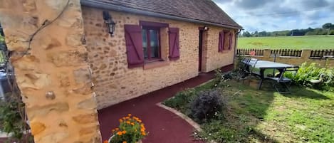 Un bâtiment en pierre avec un chemin rouge menant à une table et à des chaises à l’extérieur.