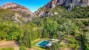 Area piscina con vasca quadrata, circondata da verde e alberi, con montagne sullo sfondo.