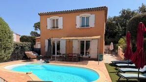 Une piscine avec des chaises longues et un espace patio.