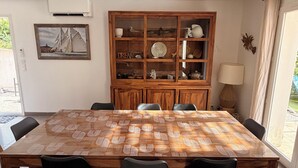 Un coin repas avec une table en bois, des chaises noires, un meuble avec des portes en verre et un tableau encadré au mur.
