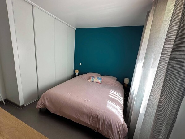 Une chambre avec un lit simple, une table de chevet, une lampe et une armoire.