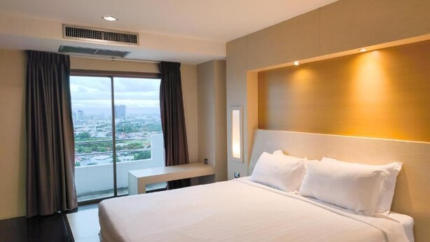 A hotel room with a large bed, a desk, and a view of the cityscape. - Avana Bangkok Hotel & Convention Centre (Bangkok)