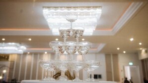 A chandelier with multiple tiers of clear glass bulbs in a well-lit room with a high ceiling. - Avana Bangkok Hotel & Convention Centre (Bangkok)