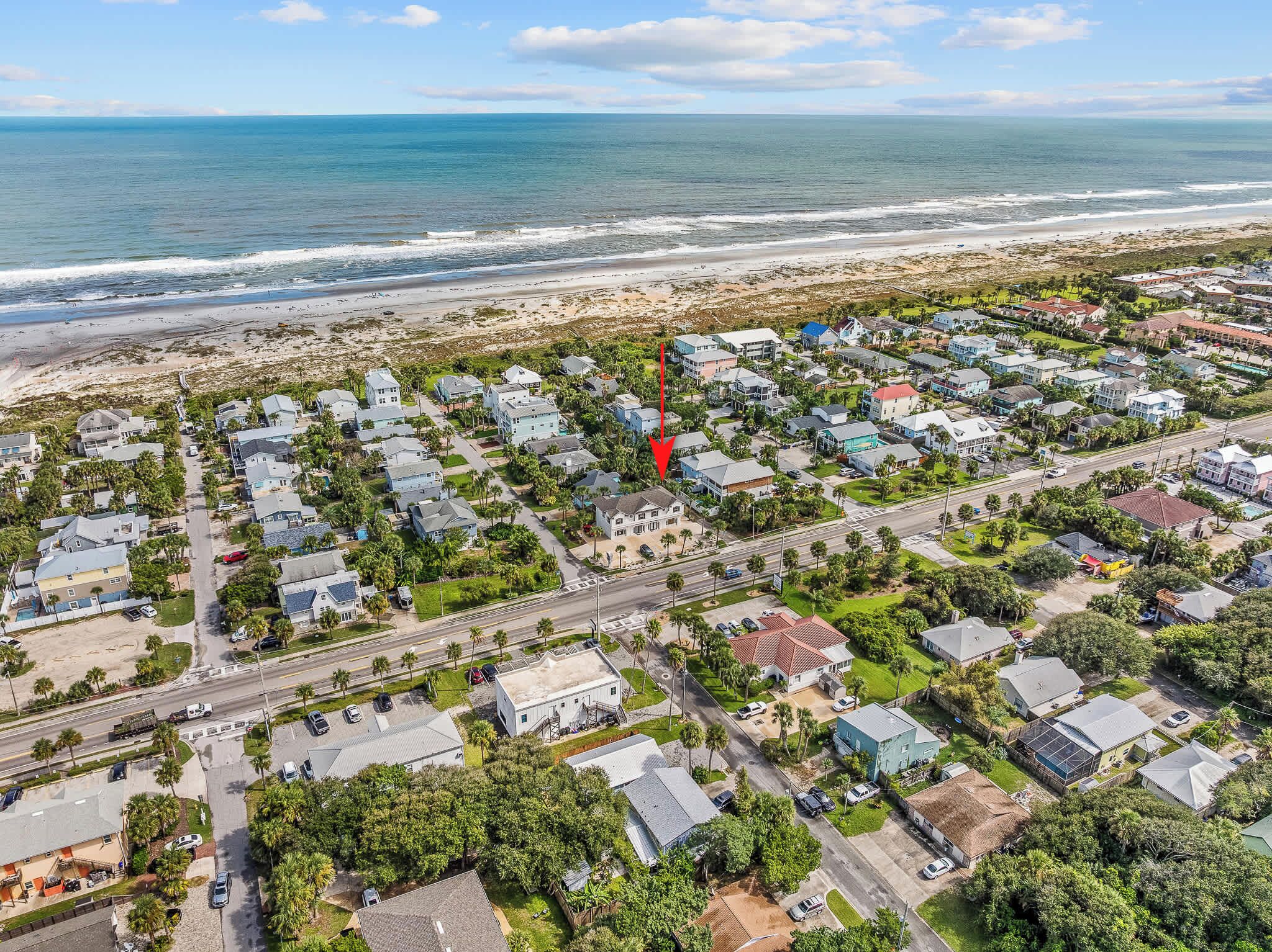 An aerial view of a coastal residential area with houses, roads, and a beach.