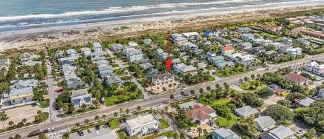 An aerial view of a coastal residential area with houses, roads, and a beach.