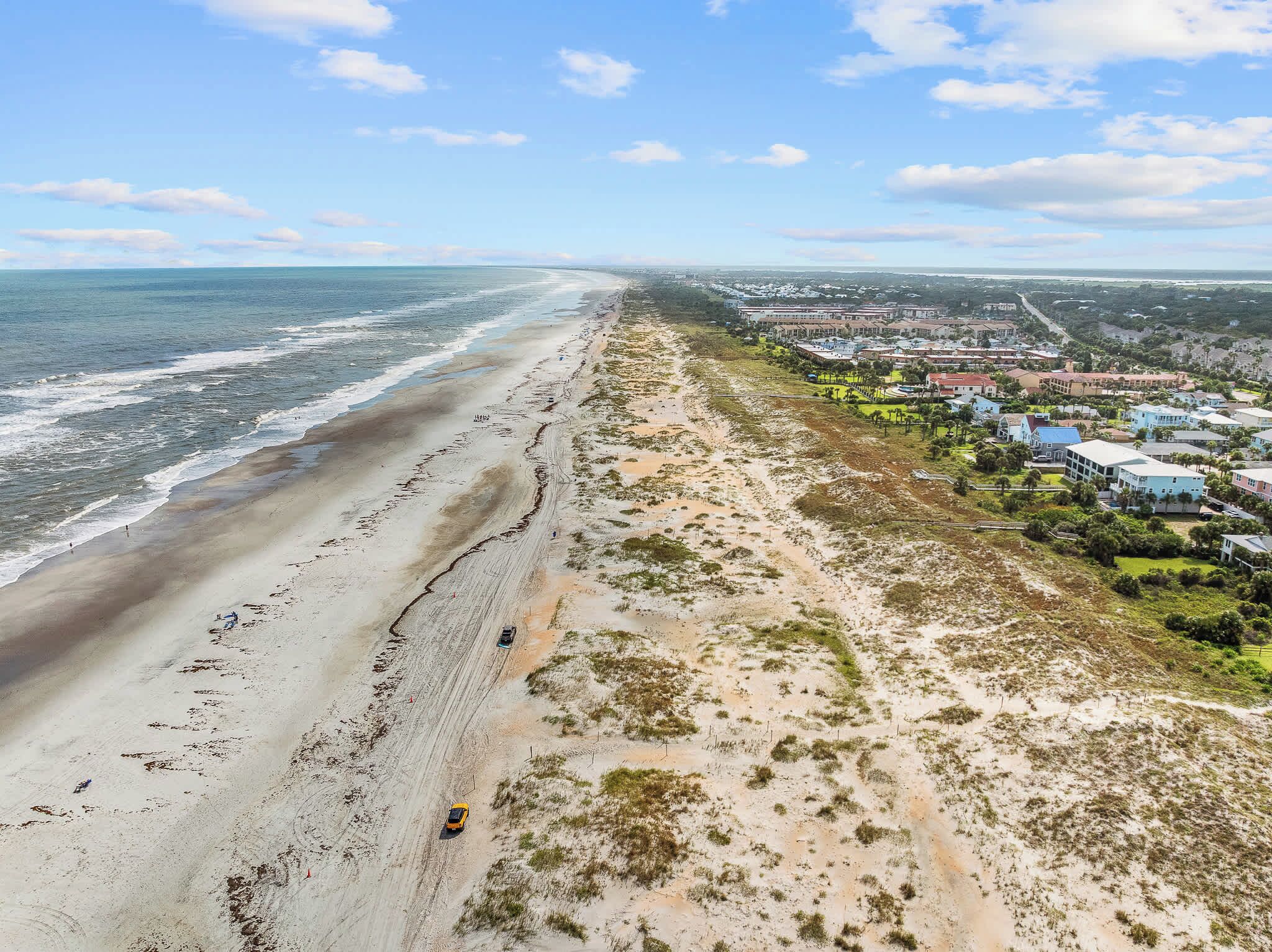 Eine Küstenregion mit Strand, einer Straße und einem Wohngebiet mit Häusern.