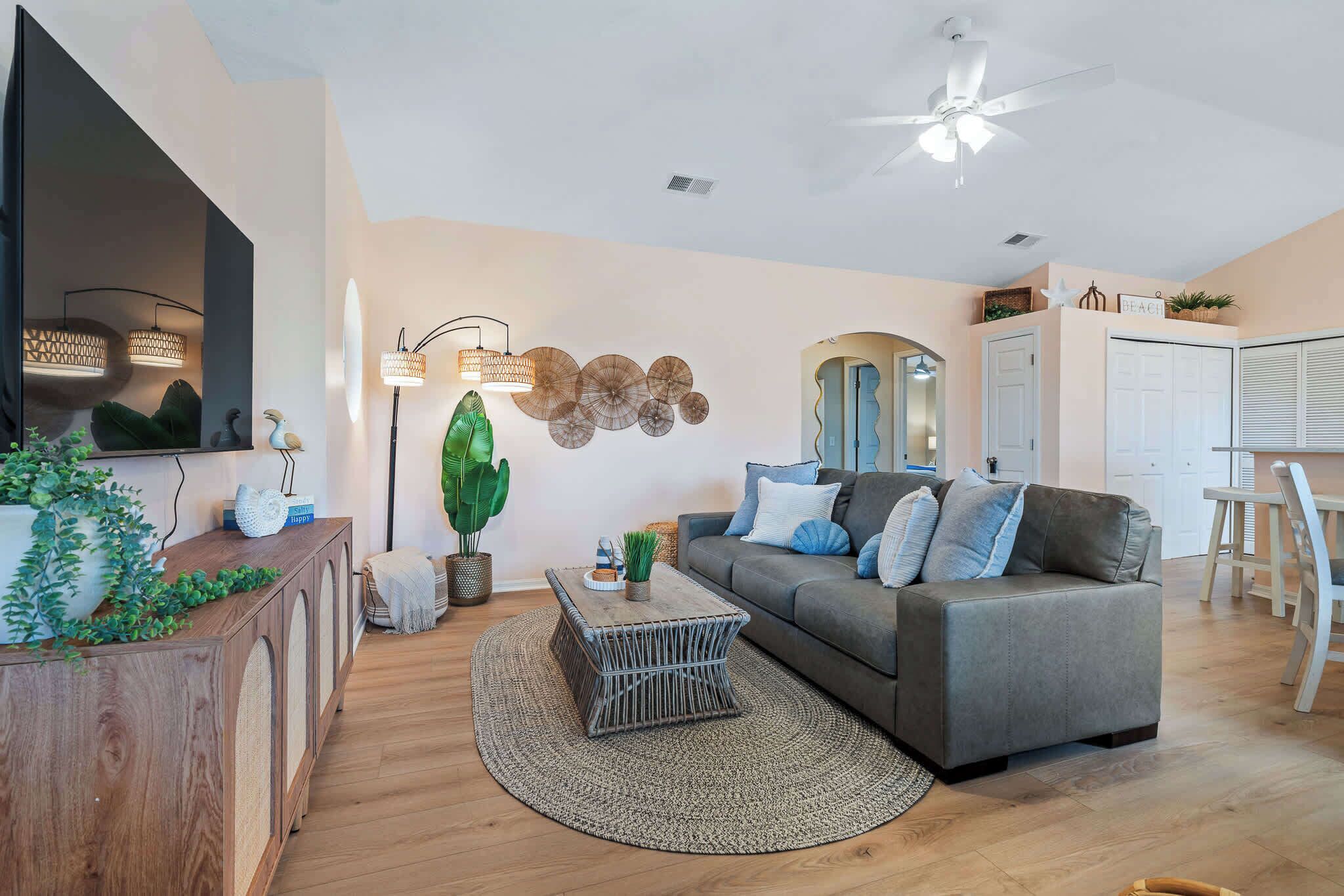 A modern living room with a grey sofa, a wooden console table, a round coffee table, and a large green plant.