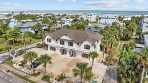 A two-story house with a garage, surrounded by palm trees and a view of the ocean. - Just Beachy l Steps to Beach l Walk to Restaurants (St. Augustine)