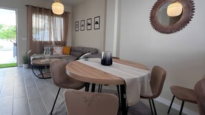 A modern dining area with a round table, chairs, pendant lights, and a decorative mirror on the wall.