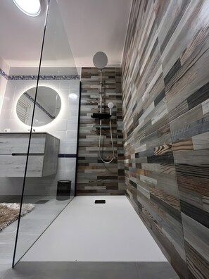 A modern bathroom with a shower, a round mirror, and a vanity with a marble countertop.
