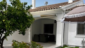 A house with a covered patio, a garden with artificial grass and stepping stones, and a view of the backyard.