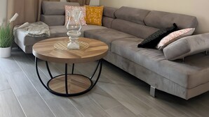 A modern living room with a grey sofa, a round wooden coffee table, and a pendant light.