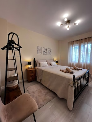 Quarto com cama, mesa de cabeceira, luminária, escada, cadeira e janela com cortinas.