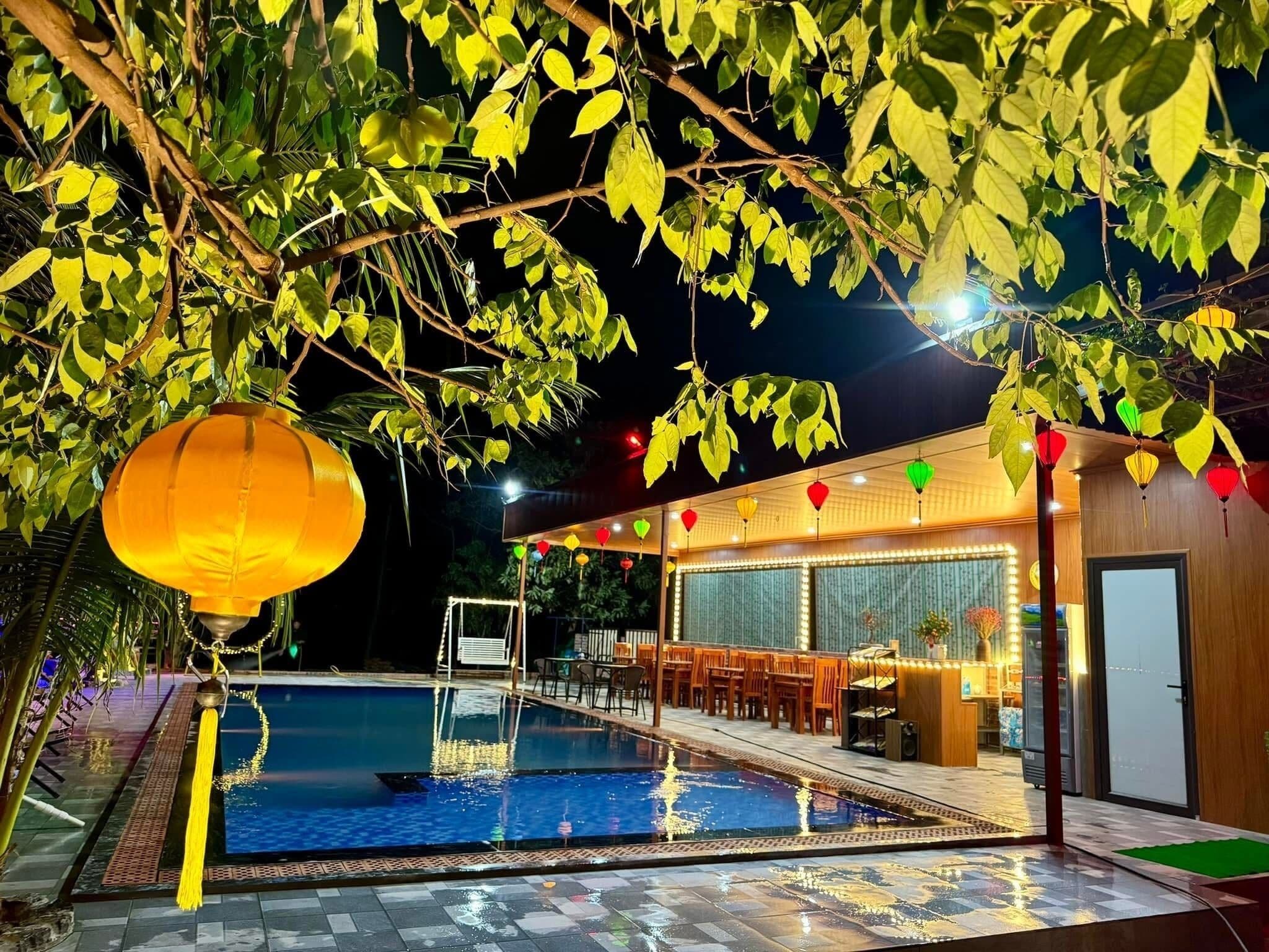 Un área de piscina con fuente de agua, un comedor con mesas y sillas, y un edificio con grandes ventanales.