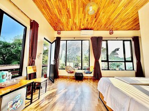 A room with a wooden ceiling, large windows, a bed, a desk, and a chair. - Tràng An Dragon Homestay (Ninh Binh)