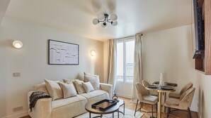 A modern living room with a sofa, coffee table, and dining area. - New apartment Center of Paris/Le Marais (Paris)