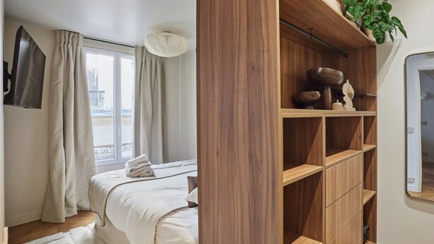A bedroom with a bed, a wooden shelf unit, and a window with curtains. - New apartment Center of Paris/Le Marais (Paris)