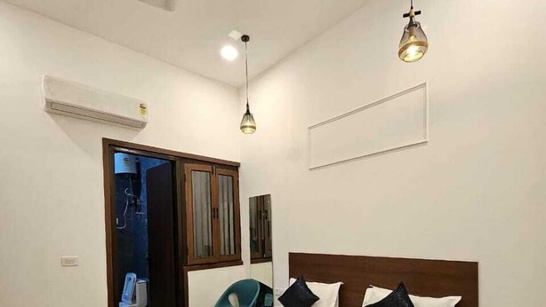 Une chambre à coucher avec un lit, un ventilateur de plafond et des luminaires suspendus.