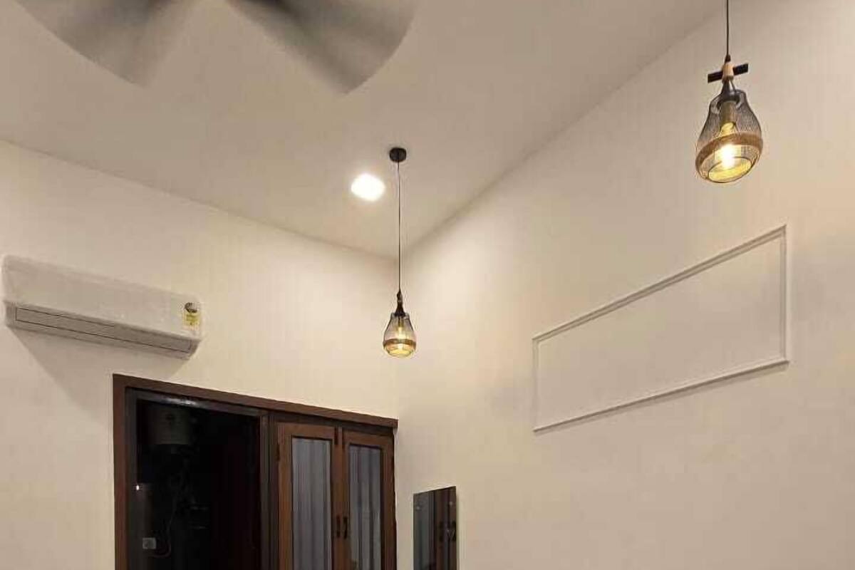A bedroom with a bed, a ceiling fan, and a hanging light fixture.