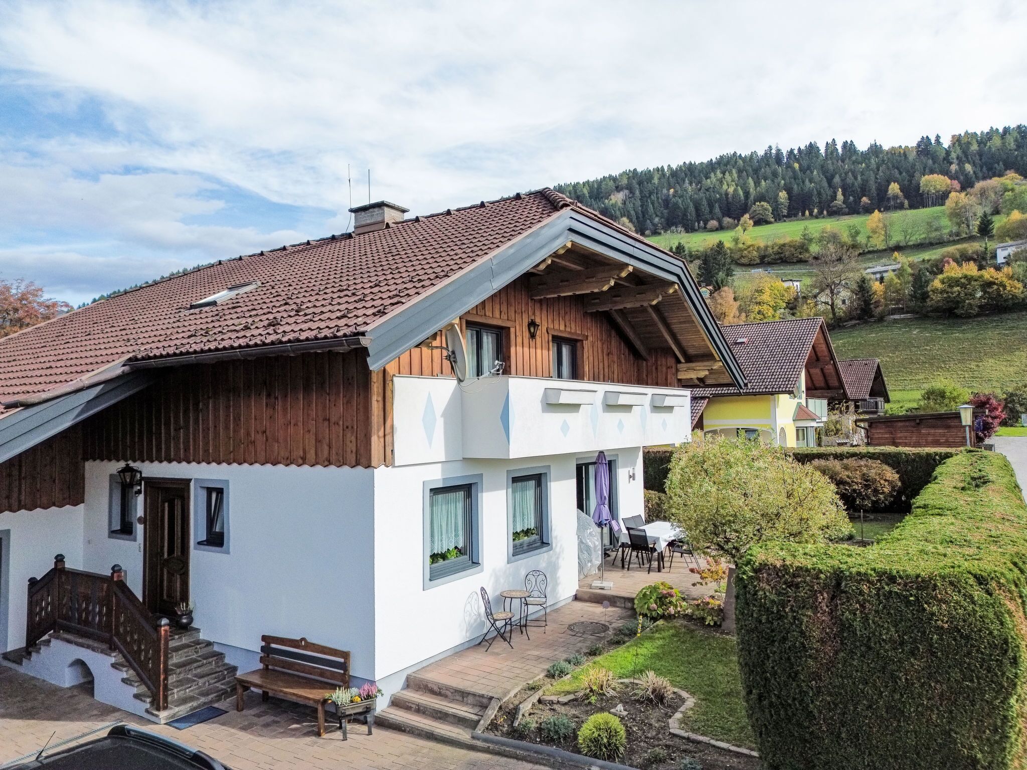 A two-story chalet with a sloped roof, wooden exterior, and a balcony.