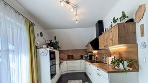 Kompakti keittiö, jossa on valkoiset kaapit, puinen työtaso ja sisäänrakennettu uuni.