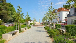 A paved pathway leading to a building with a white facade and a red roof.