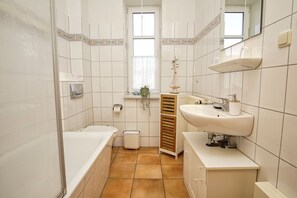 Ein Badezimmer mit Badewanne, Toilette, Waschbecken und Fenster.