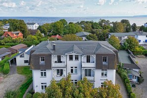 Ein mehrstöckiges Gebäude mit Balkon, umgeben von Bäumen und Blick auf das Meer.