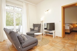 A living room with a sofa, armchair, TV, and a small side table.