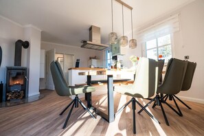 A modern kitchen with a central island, a wood-burning stove, and pendant lighting.