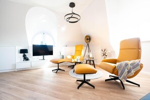 A modern living room with a high ceiling, a flat-screen TV, and a round coffee table.