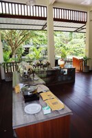 Montaje de bufé con varias estaciones de servicio, una mesa de madera y vista a la vegetación exuberante.