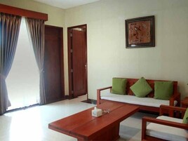 Una habitación con un sofá de madera, una mesa de centro de madera y un cuadro en la pared.
