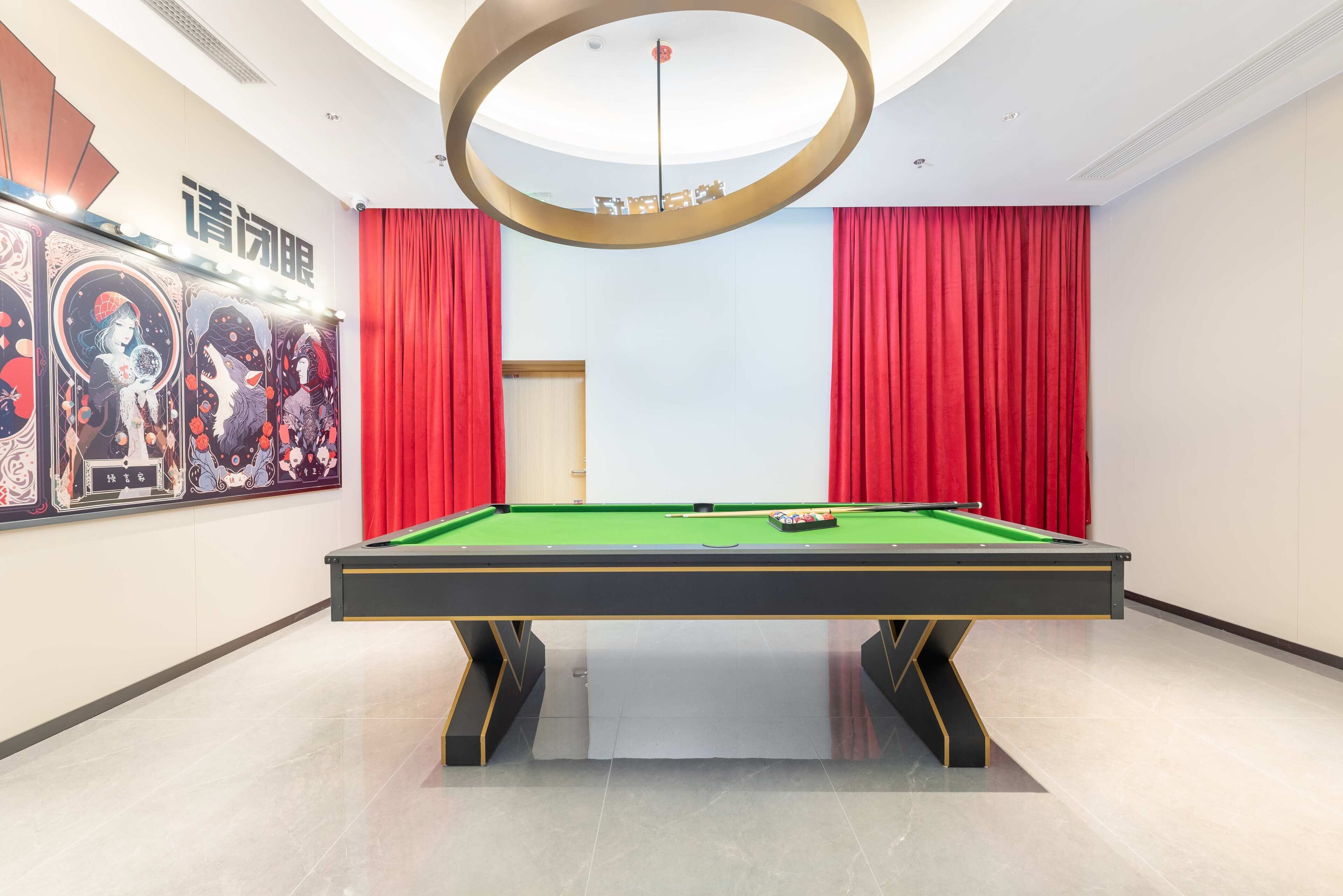 A pool table in a room with red curtains and artwork on the walls.