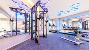 A gym with various exercise equipment, mirrors, and a treadmill. - Lemon Hotel- New World Shopping Mall (Wuhan)