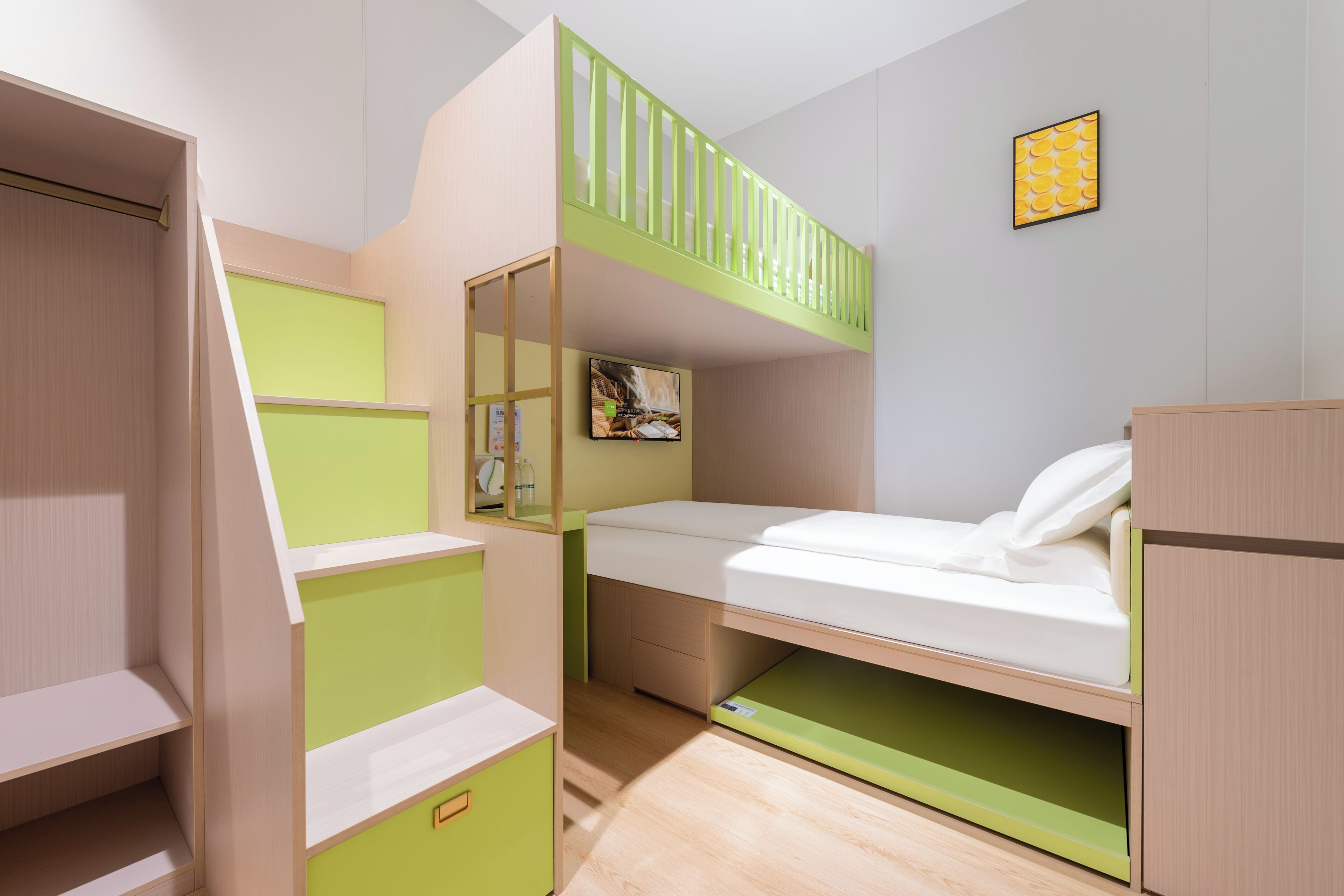 Une chambre avec un lit superposé, une échelle verte, un bureau et un petit placard.