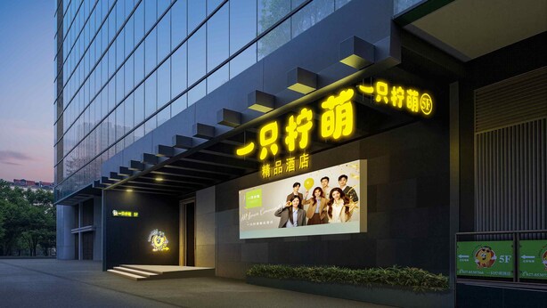 A modern hotel entrance with a large illuminated sign, a staircase leading to the entrance, and a billboard advertising the hotel. - Lemon Hotel- New World Shopping Mall (Wuhan)