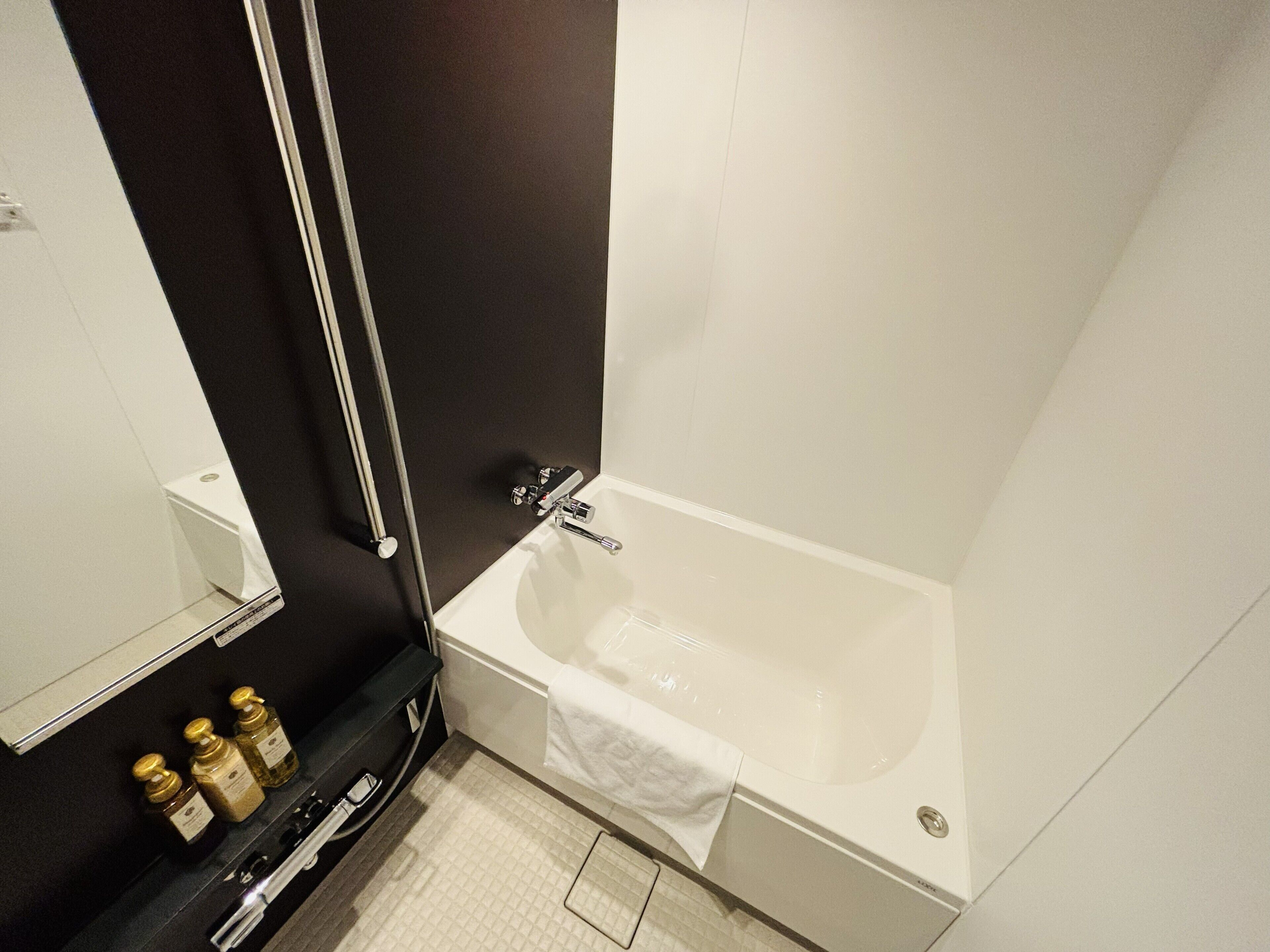 Un baño moderno con una bañera, un inodoro y un espejo. Hay botellas de artículos de aseo en el mostrador.