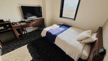 Habitación de hotel con cama, escritorio, televisor y ventana con vista a la ciudad.