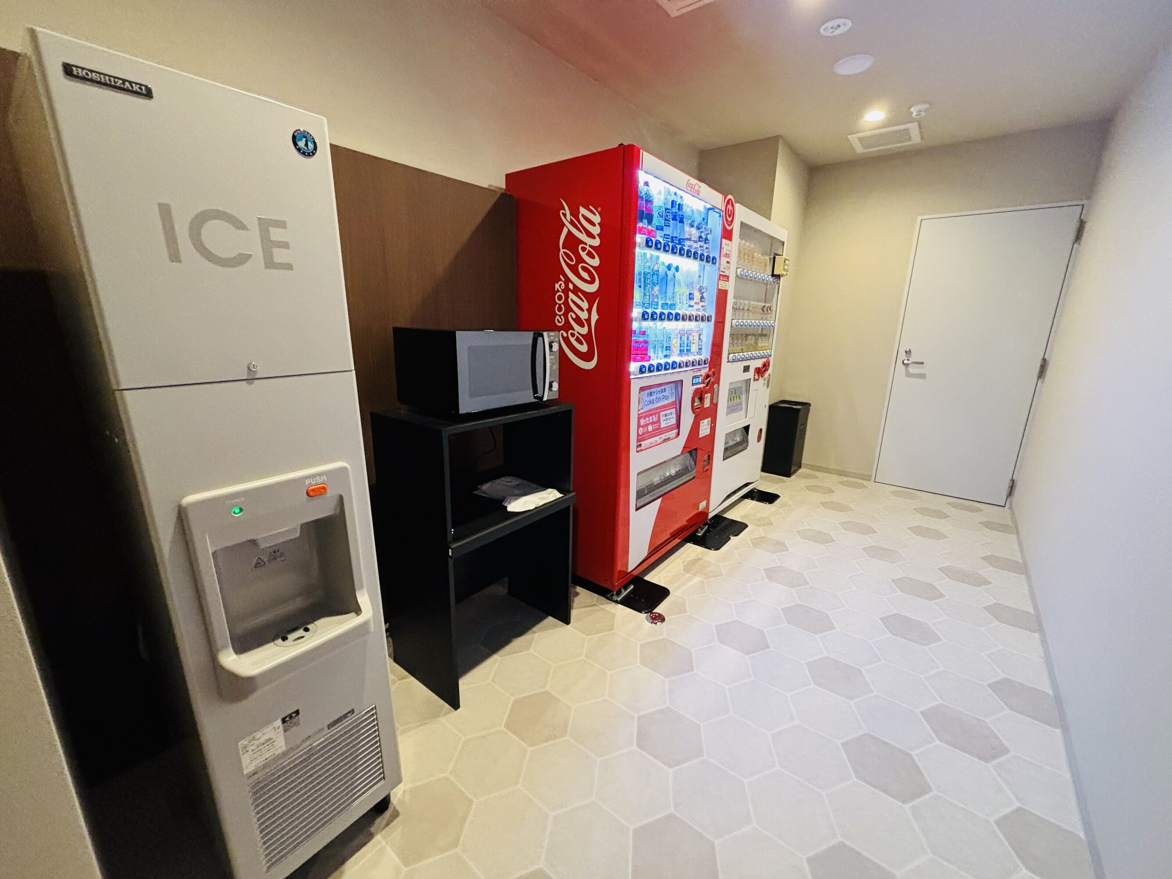 A vending area with an ice dispenser, a microwave, and a Coca-Cola vending machine.