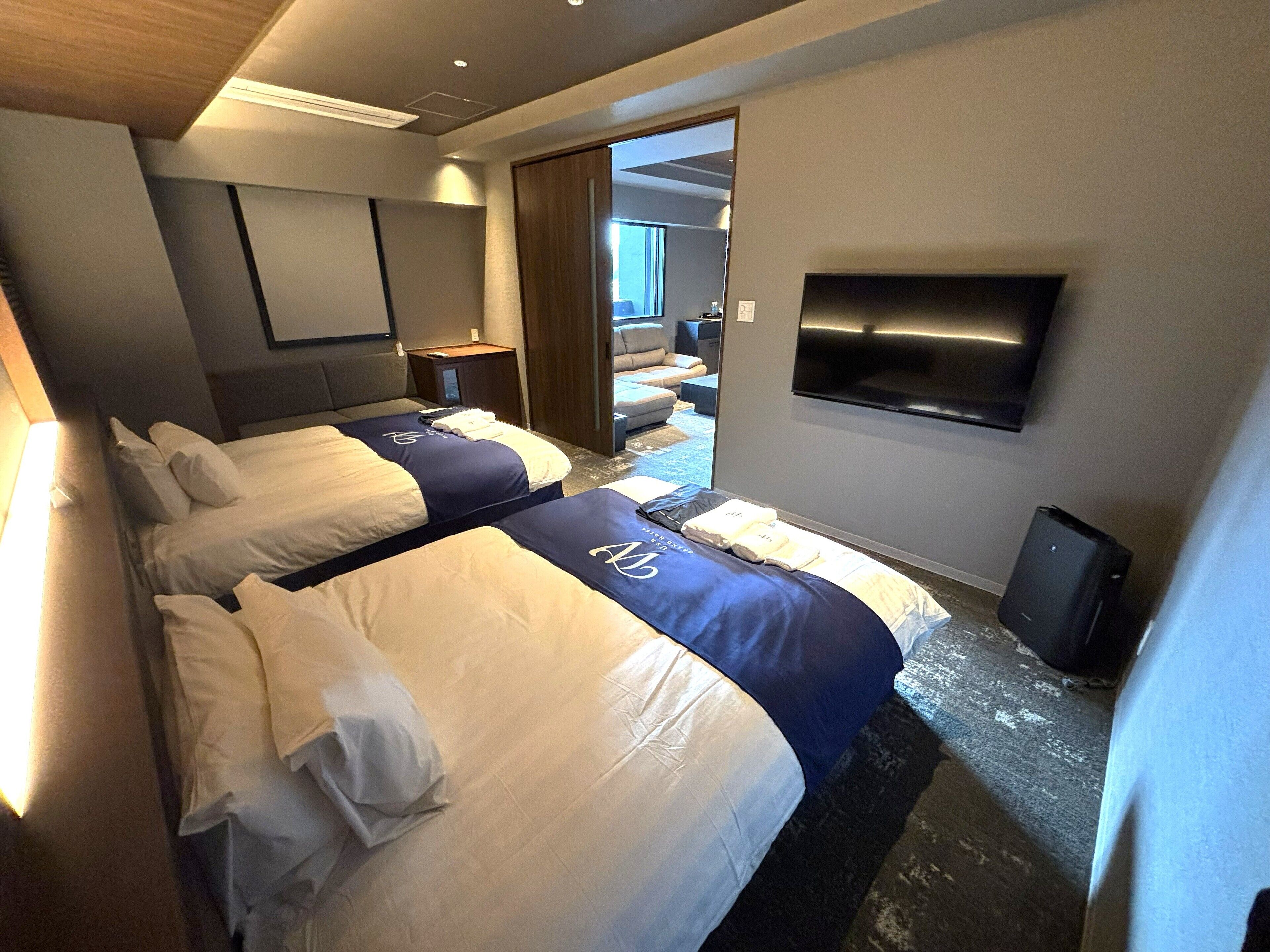 Habitación de hotel con dos camas, televisión, escritorio y vistas al exterior.