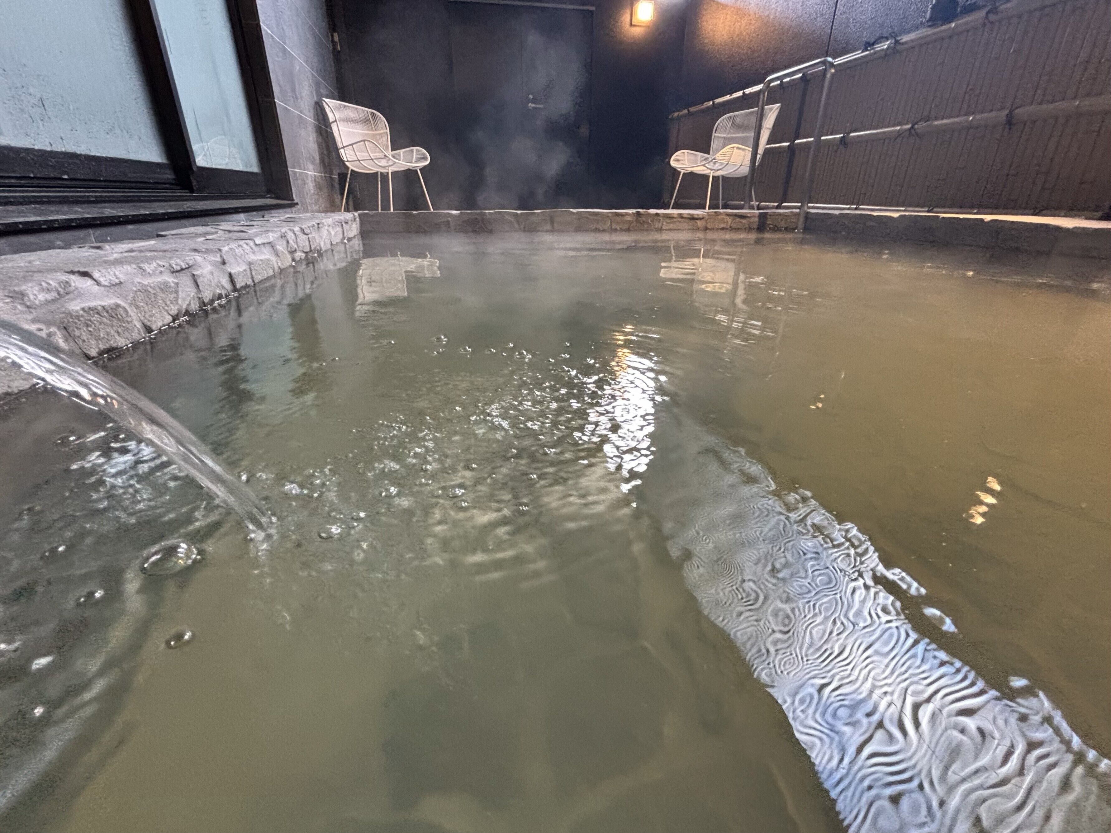 A hot spring area with two white chairs and a water feature.